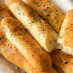 Use bread flour instead of all-purpose flour for a slightly chewier texture. Make sure the water is warm, not hot, to properly activate the yeast. Do not skip the second rise, as it helps create soft and fluffy breadsticks. Brush with garlic butter while the breadsticks are still hot so the flavor absorbs better. Store leftovers in an airtight container for up to 2 days at room temperature or 5 days in the refrigerator. Reheat in the oven or air fryer for the best texture.